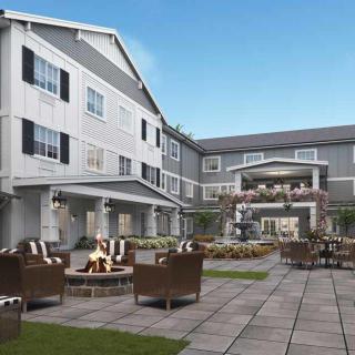 Outdoor patio area with seating and a fire pit in front of a multi-story building.