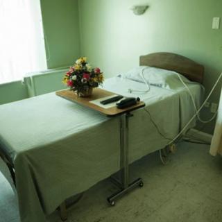 An empty hospital room with a medical bed and flowers on a table.