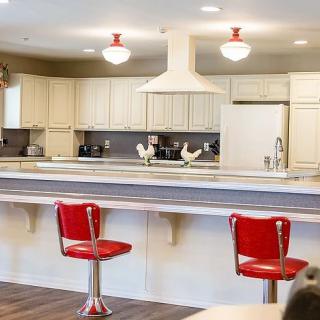 A modern kitchen with red bar stools and white cabinetry.