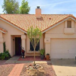 A single-story suburban house with a garage and a small tree in the front yard.