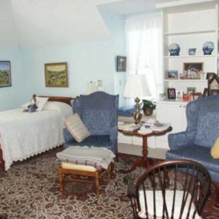 A cozy living area with a bed, blue chairs, and decorative items.