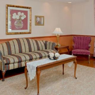 A cozy living room setup featuring a striped sofa, an elegant armchair, and a tasteful coffee table adorned with decorative items.