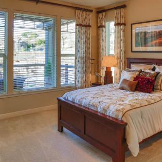 A cozy and well-decorated bedroom with large windows and warm lighting.