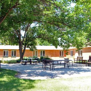 A serene outdoor patio area with tables and chairs, surrounded by trees and buildings.