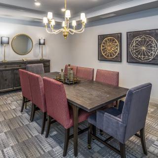 A modern dining room with upholstered chairs and elegant chandelier.