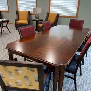 A meeting room featuring a large wooden table surrounded by chairs with colorful upholstery.