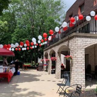 Outdoor event area decorated with red and white balloons, tables, and chairs.