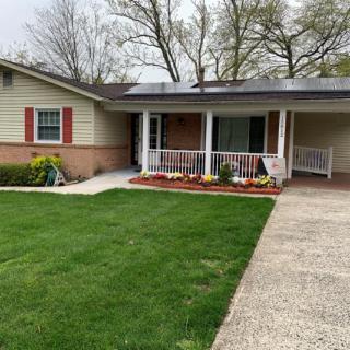 A suburban house with a green lawn and porch.