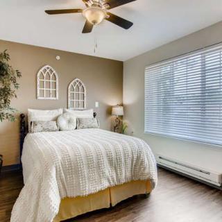 A cozy bedroom with a soft bed, decorative wall art, and a large window allowing natural light.