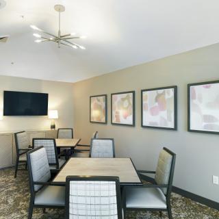 A modern meeting room with tables and chairs, decorated with artwork and equipped with a television.
