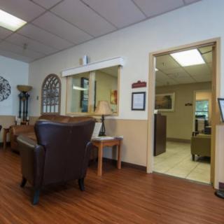 A well-furnished waiting room with comfortable chairs and a reception desk.