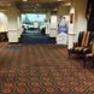 A carpeted hallway with chairs leading to a conference area in a hotel.