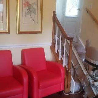 A cozy living space featuring two red chairs and a staircase with framed artwork on the wall.