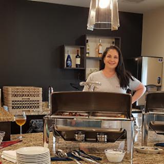 A woman stands confidently in a professional kitchen, ready to serve delicious food.