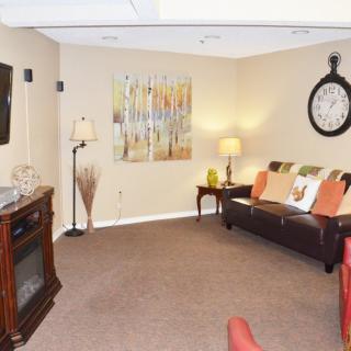 A cozy living room with a sofa, wall clock, and contemporary artwork.