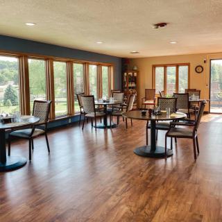 A bright dining area with tables, chairs, and large windows allowing natural light.
