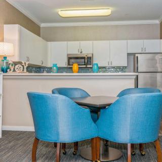 A modern kitchen with stainless steel appliances and a cozy dining area featuring blue chairs.