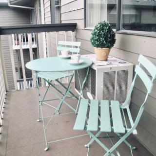 A cozy balcony setup with pastel-colored outdoor furniture and a potted plant.