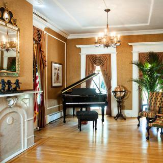 A classic living room featuring a grand piano, chandelier, and elegant decor.