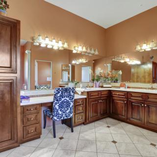A spacious bathroom featuring a large vanity with multiple mirrors and elegant lighting.