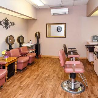 A cozy salon interior featuring chairs, hair dryers, and a waiting area.