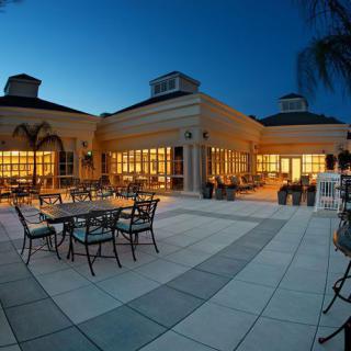 A luxurious outdoor patio area illuminated at night, featuring elegant dining tables and chairs.