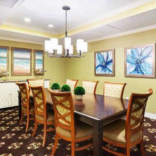 A modern dining room featuring a large wooden table, elegant chandelier, and contemporary artwork on the walls.