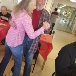 An elderly couple joyfully dancing together at a social gathering.