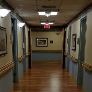 A dimly lit hallway with wooden flooring and artwork on the walls.