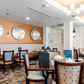 A modern dining area with neatly arranged tables and chairs, decorated with mirrors on the wall.