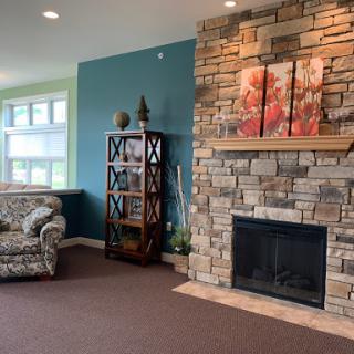 A cozy living room featuring a stone fireplace, stylish shelves, and comfortable seating.