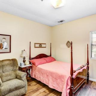 A cozy bedroom with a four-poster bed, an armchair, and wall art.