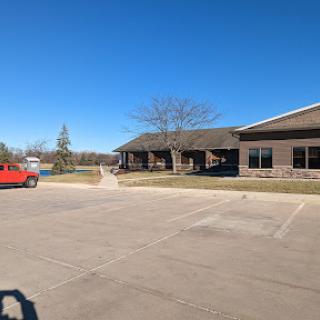 A scenic view of a building with a red car parked in the foreground under a clear blue sky.