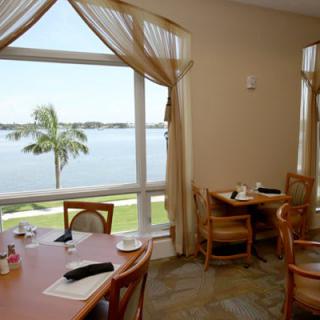 A tranquil restaurant dining area with a picturesque view of the lake through large windows, featuring tables and chairs arranged for patrons.