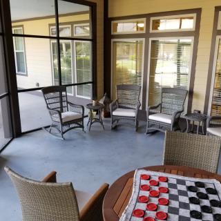A cozy screened porch with seating and a chessboard on the table.
