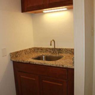 A compact kitchenette area with a granite countertop and wooden cabinets.