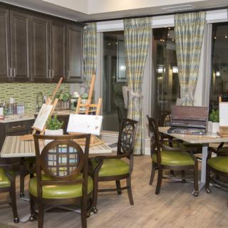 A modern kitchen and dining area with art supplies on the tables, featuring stylish seating and patterned curtains.
