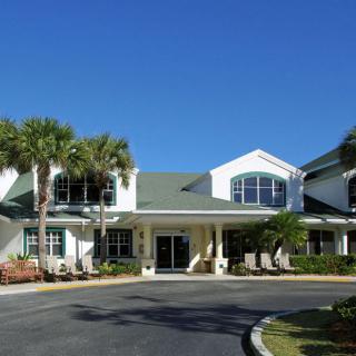 A large residential building with palm trees and a clear blue sky.