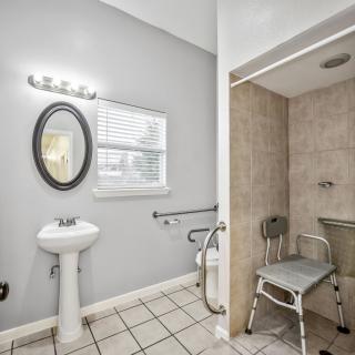An accessible bathroom with a shower, sink, and grab bars.