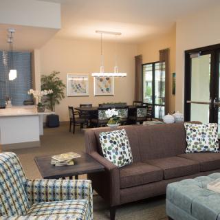 A modern open-space living room featuring a comfortable sofa, dining area, and kitchen.