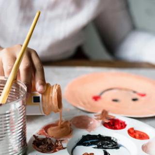 A person engaged in a watercolor painting activity, with a color palette and paintbrushes nearby.
