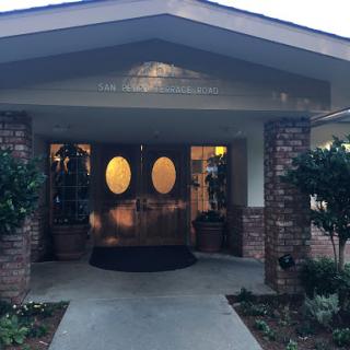 A welcoming entrance to a building with decorative plants and circular windows.