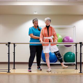A physical therapist assists an elderly patient during a rehabilitation session focusing on balance and strength.