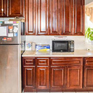 A kitchen with wooden cabinets, a stainless steel refrigerator, and a microwave on the countertop.