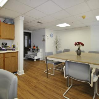 A modern meeting room with a large table, several chairs, and decorative elements like a vase with flowers.