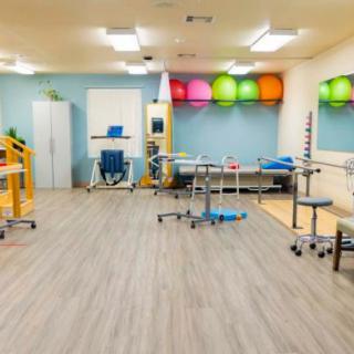 A well-equipped physical therapy and rehabilitation room with exercise equipment and gym balls.