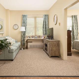 A cozy living room with a pastel sofa, wooden TV stand, and natural light coming through the windows.