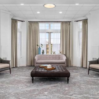 A modern living room with neutral tones, featuring a sofa, armchairs, and a central coffee table.