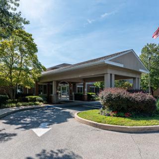 A welcoming entrance to a hotel surrounded by trees and greenery.