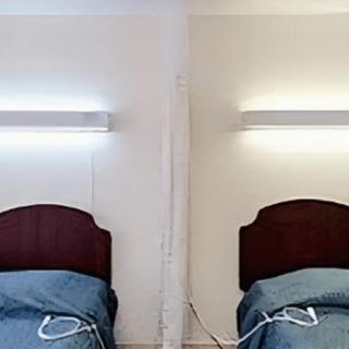 A hospital room with two beds and wall-mounted lights.